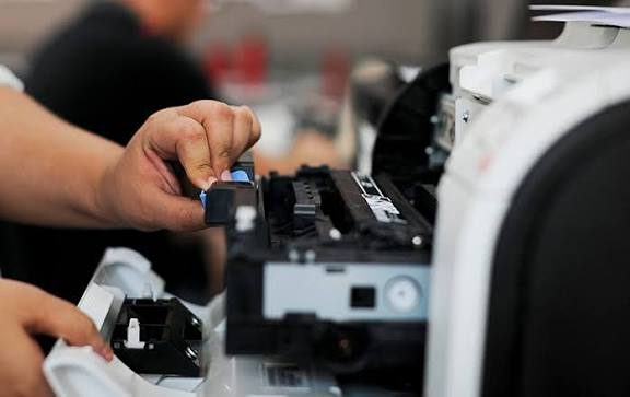 Técnico fazendo manutenção no interior de uma impressora