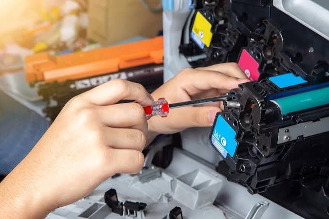 Técnico com chave de fenda em cartucho de toner de multifuncional colorida aberta
