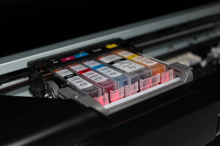 Bandeja de cartuchos de tinta coloridos organizados sobre fundo preto